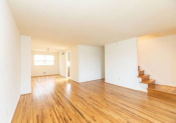 Empty living room with a hard wood floor and white walls